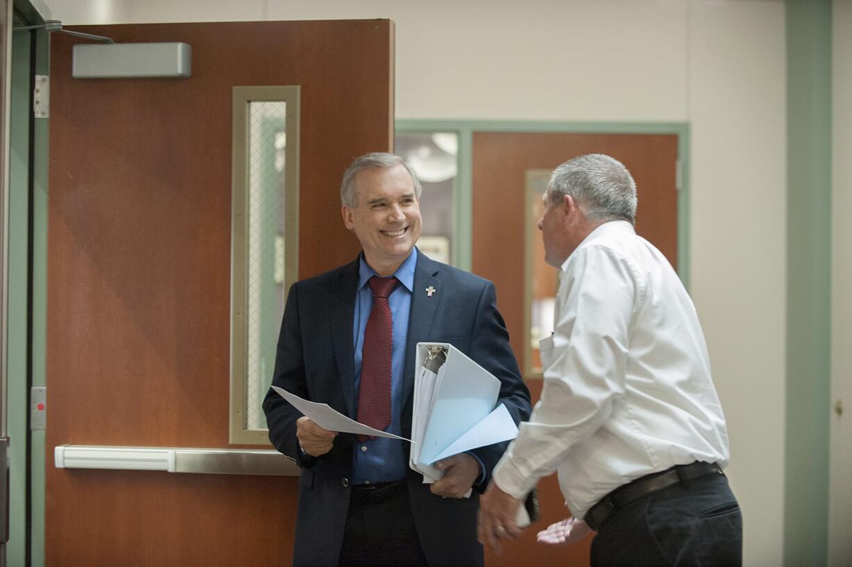 Clark County Councilor David Madore, left, is served with a summons by process server Brian Davis to appear at a deposition in connection with Oliver Orjiako's lawsuit against him, Tuesday morning at the Clark County Public Service Center in Vancouver.