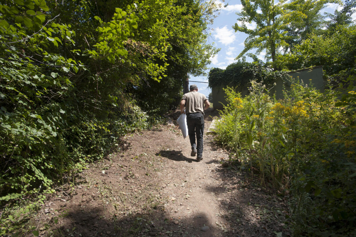 Contractor Art Rojsza walks along the trail at Wintler Park while holding plans for a new set of stairs he&#039;s building.