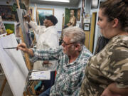 Painter, teacher and gallery owner Blue Bond, center, gives Olga Miller some instruction in creating underlying textures for a new painting while Lee Jenkins, in background, puts some finishing touches on a portrait of his wife.