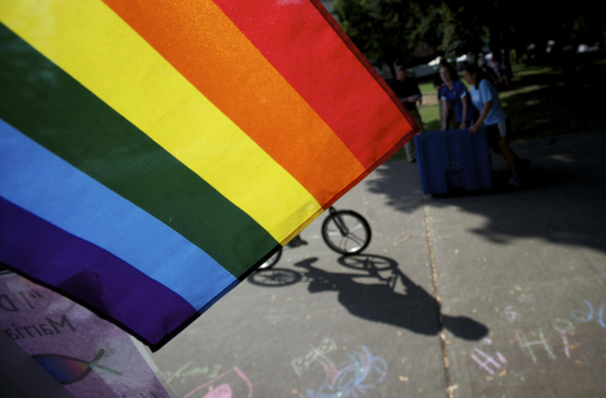 A bicyclist rides past a rainbow flag during the 2012 Pride in the Park event at Esther Short Park in downtown Vancouver.