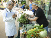 Dr. Mehrdad Shojaei and chef Sebastian Carosi of Coyote Ridge Ranch in La Center talk about produce at the Salmon Creek Farmers Market at Legacy Salmon Creek Medical Center on July 26.