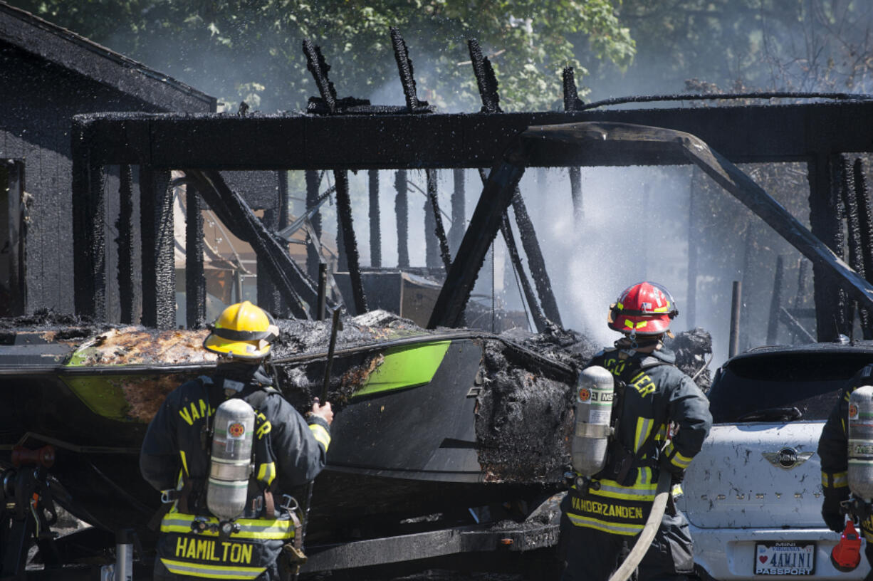 Smoke billows around cars and a boat as firefighters extinguish a fire Thursday afternoon at 7115 N.E. 139th St.