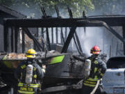 Smoke billows around cars and a boat as firefighters extinguish a fire Thursday afternoon at 7115 N.E. 139th St.