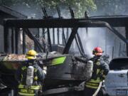 Smoke billows around cars and a boat as firefighters extinguish a fire Thursday afternoon at the corner of Northeast 72nd Avenue and Northeast 139th Street.