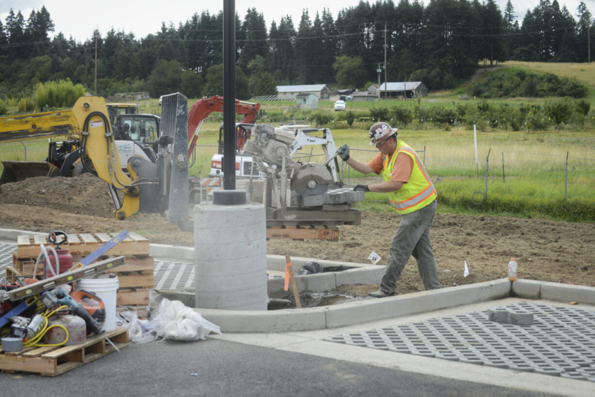 Chris Milton uses a diamond blade to cut a concrete paver at the 78th Street Heritage Farm earlier this month. The parking lot will test several types of paving surfaces that allow rainwater to permeate into the ground, avoiding runoff.