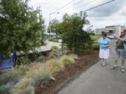 Rene Jordan, owner of Peach Willow Spa in Vancouver, talks with passerby Randall Hollaus about her garden being featured in the &quot;Pokemon Go&quot; game Friday.