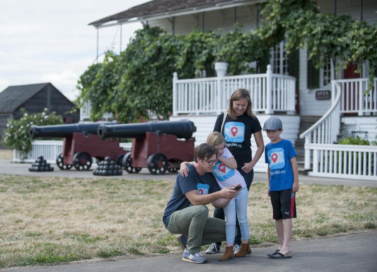 Tim Fry, from left, shows daughter Ruby, wife Kristine and son Henry information about Fort Vancouver on his smartphone app. The family from Lopez Island is touring state historical sites after Tim Fry helped eighth-grade students develop the app.