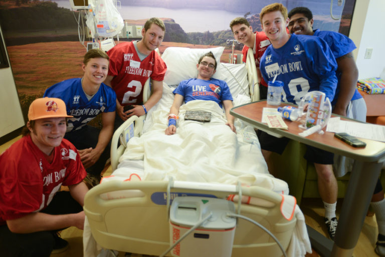 Freedom Bowl Classic football players from Clark County high schools gather around patient, Julian Lucas, 15, at Shriners Hospital in Portland Wednesday, July 6, 2016.