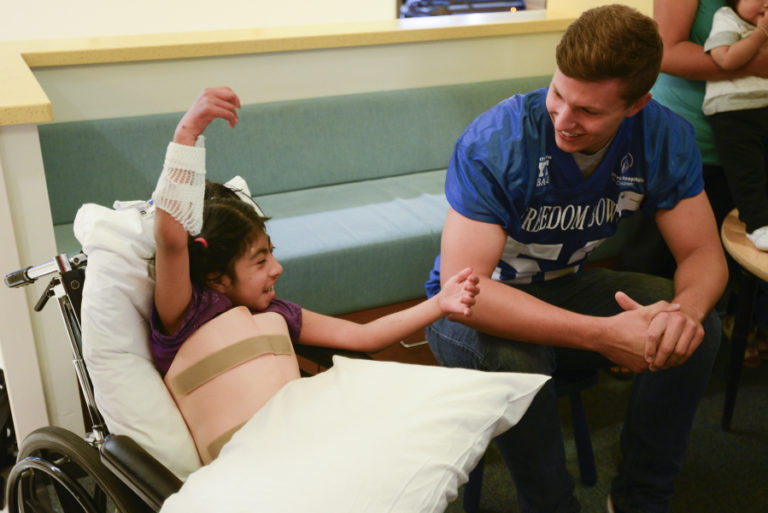 Several players from the Freedom Bowl Classic visit patient Julian Lucas.