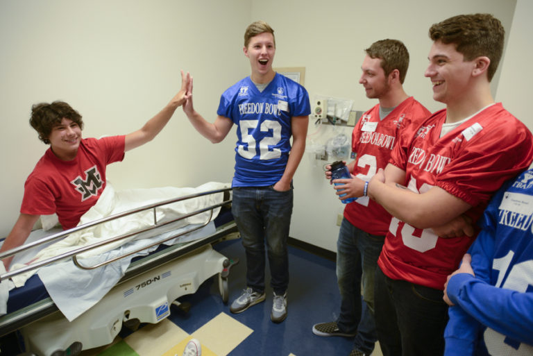 Shriners' patient, Max Freiboth, left, compares hand size with Prairie High School football player, Caleb Smith, while Dalton Morgan and Stone Sabourin stand nearby, at Shriners Hospital in Portland Wednesday, July 6, 2016. The Freedom Bowl Classic football players from Vancouver high schools visited patients at Shriners Wednesday as part of a fundraiser for the hospital.