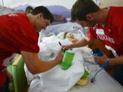 Stone Sabourin of Hudson's Bay High School, left, and Dalton Morgan of La Center High School, sign the cast of Shriner patient Julia Willis at Shriners Hospital in Portland.