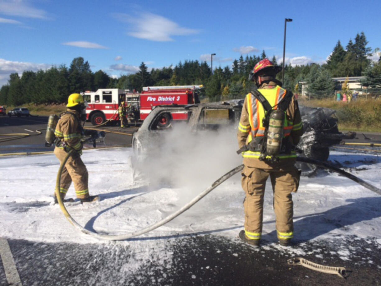 Firefighters work to extinguish a vehicle fire following a crash Tuesday evening on state Highway 503. The crash involved three vehicles, and three people were injured.