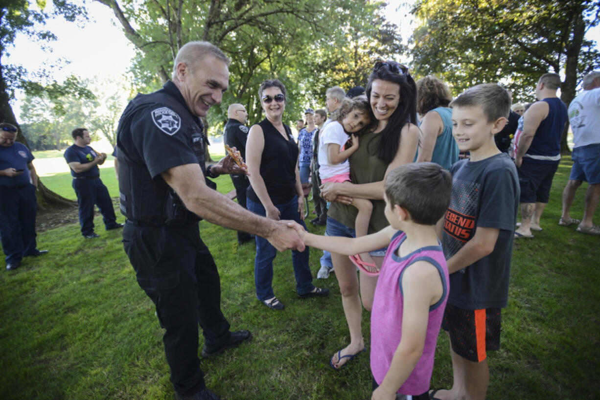 Washougal Police Department Chief Ron Mitchell, left, shakes hands with Joshua Damon, 8, at the police appreciation event at Goot Park in Camas on Wednesday evening. Jamie Damon, in green, brought her three kids to the event to honor the hard work of local law enforcement.