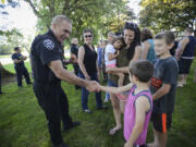 Washougal Police Department Chief Ron Mitchell, left, shakes hands with Joshua Damon, 8, at the police appreciation event at Goot Park in Camas on Wednesday evening. Jamie Damon, in green, brought her three kids to the event to honor the hard work of local law enforcement.