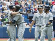 Seattle Mariners' Nelson Cruz, second from left, is embraced by teammate Kyle Seager after hitting a three-run home run in eighth-inning baseball game action against the Toronto Blue Jays in Toronto, Saturday, July 23, 2016.