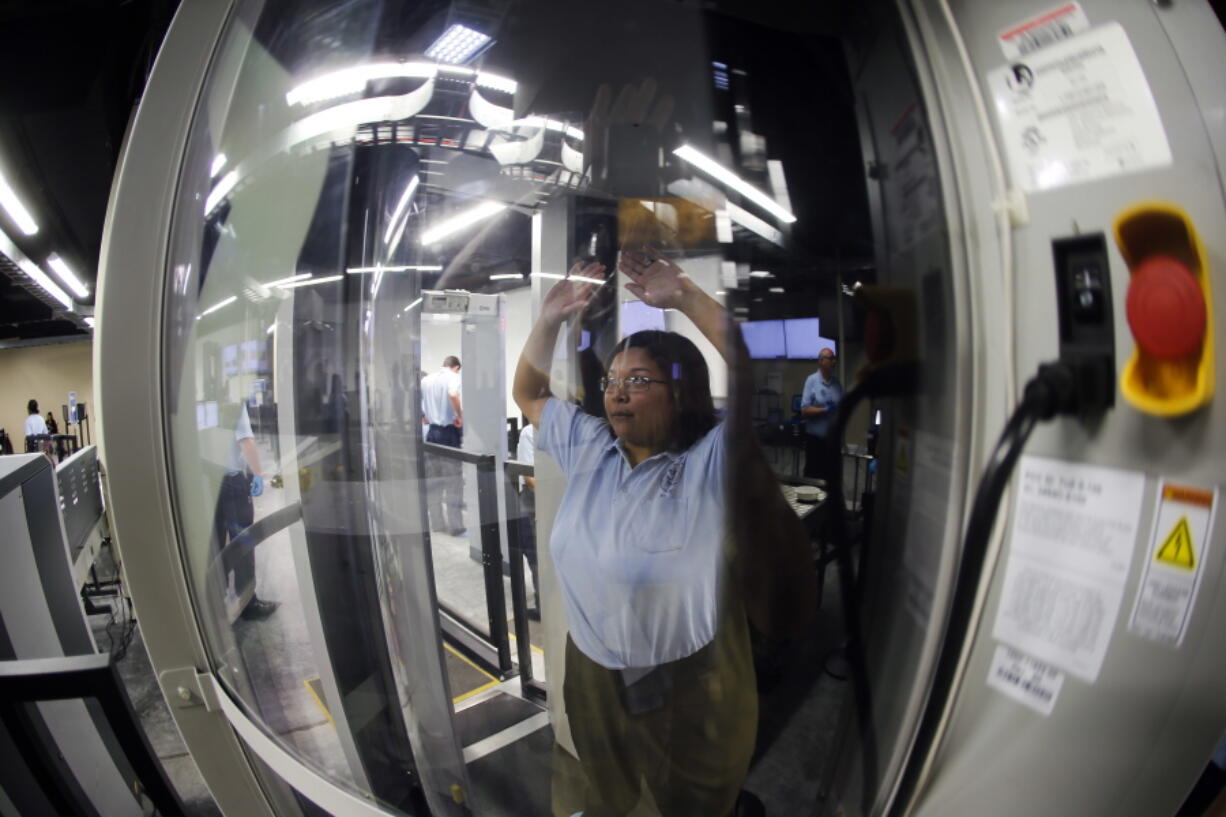 A Transportation Security Administration officer candidate passes through a body scanner as she plays the part of an air traveler during a training session in an airport security checkpoint simulator at the Federal Law Enforcement Training Center in Brunswick, Ga. Short-staffed and often criticized, the TSA aims to improve training for airport screeners.