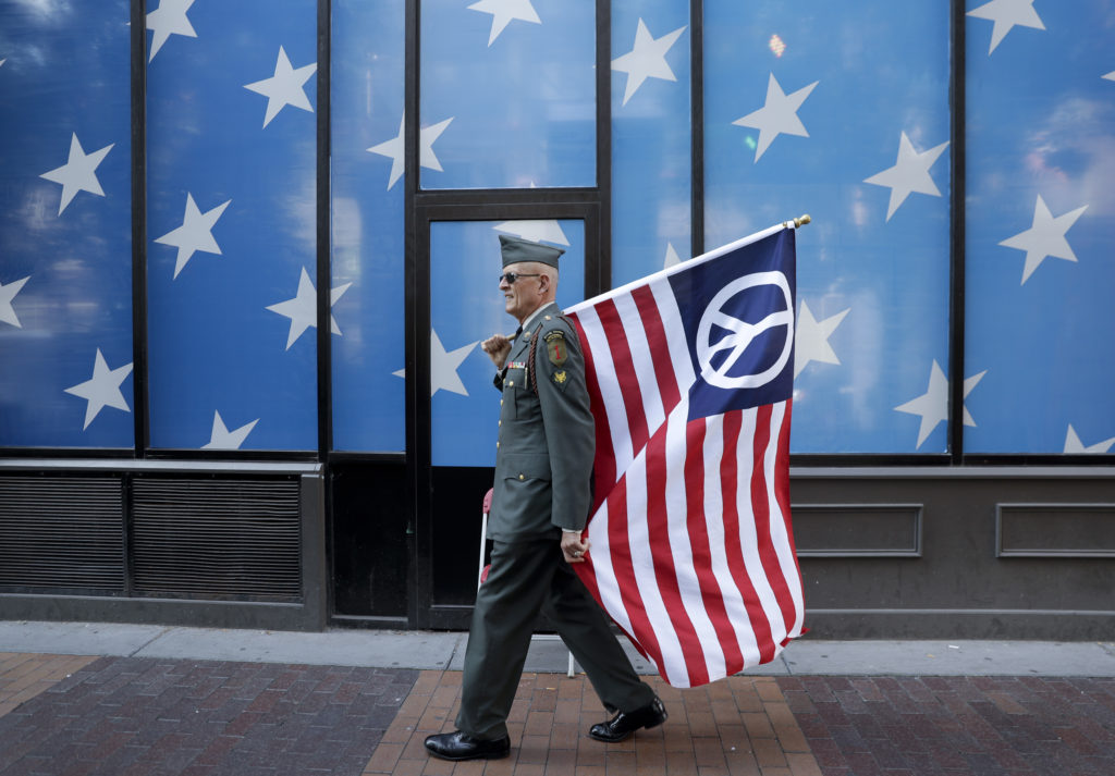 A protester carrying a peace flag walks in downtown Cleveland, Sunday, July 17, 2016, in preparation for the Republican National Convention that starts Monday.