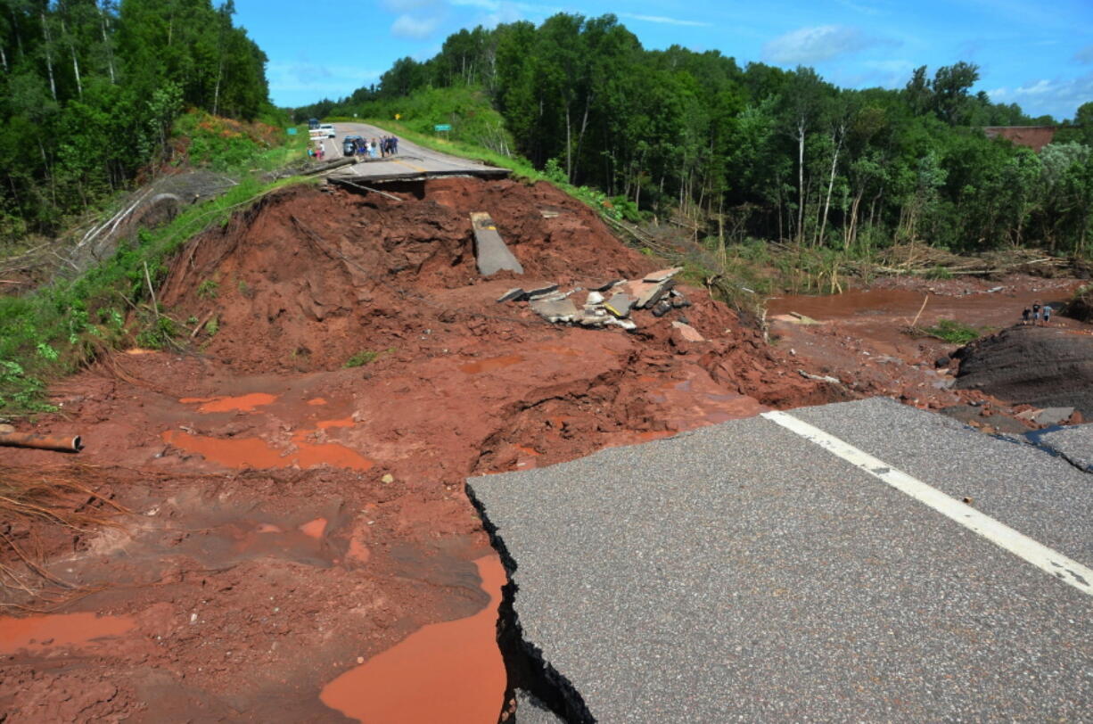 People look at a washed-out section of Wisconsin Highway 13 on Tuesday in Ashland, Wis. The road was damaged in recent heavy rains.