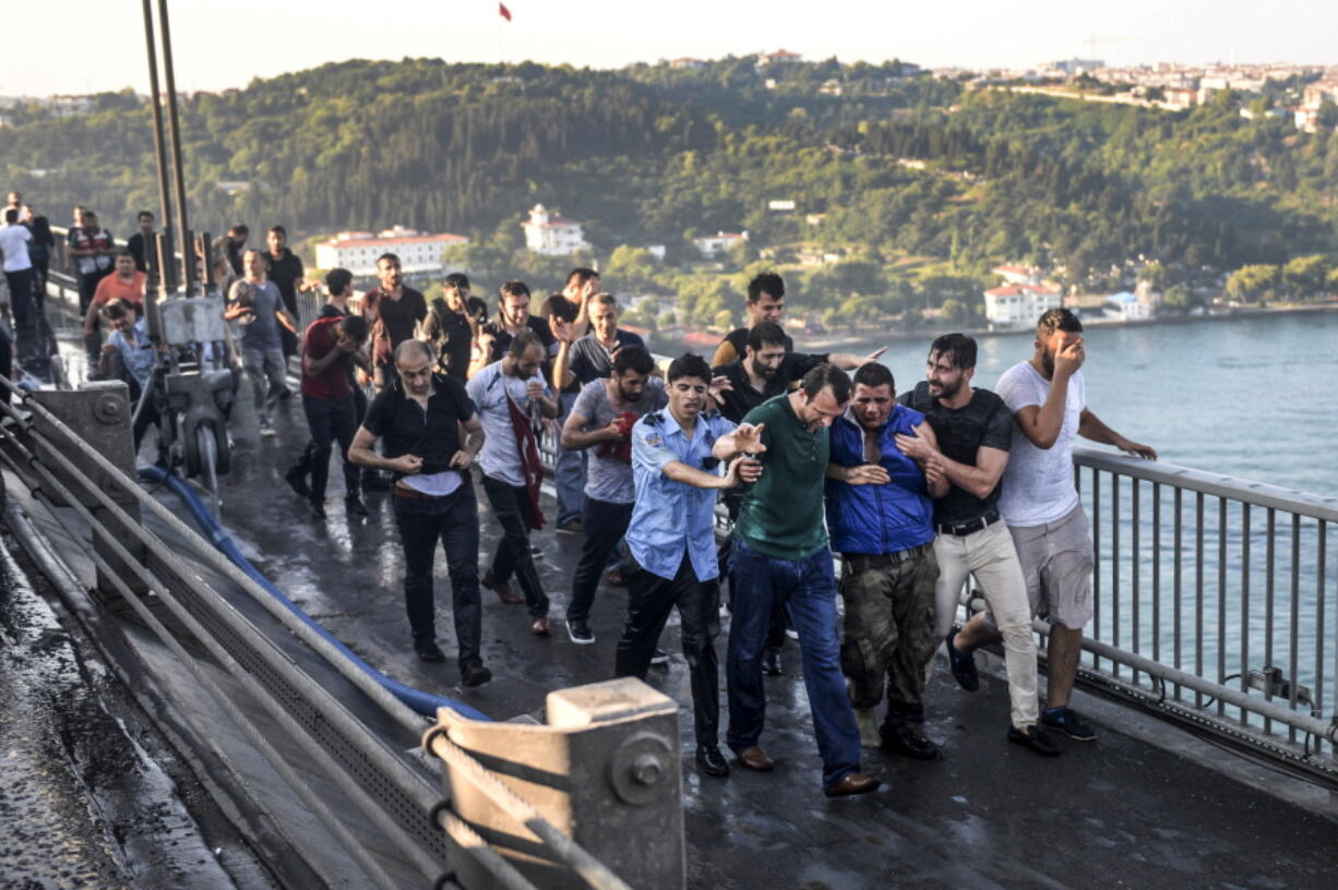 People apprehend a Turkish soldier, third right in blue, who participated in the attempted coup, on Istanbul&#039;s Bosporus Bridge, Saturday.