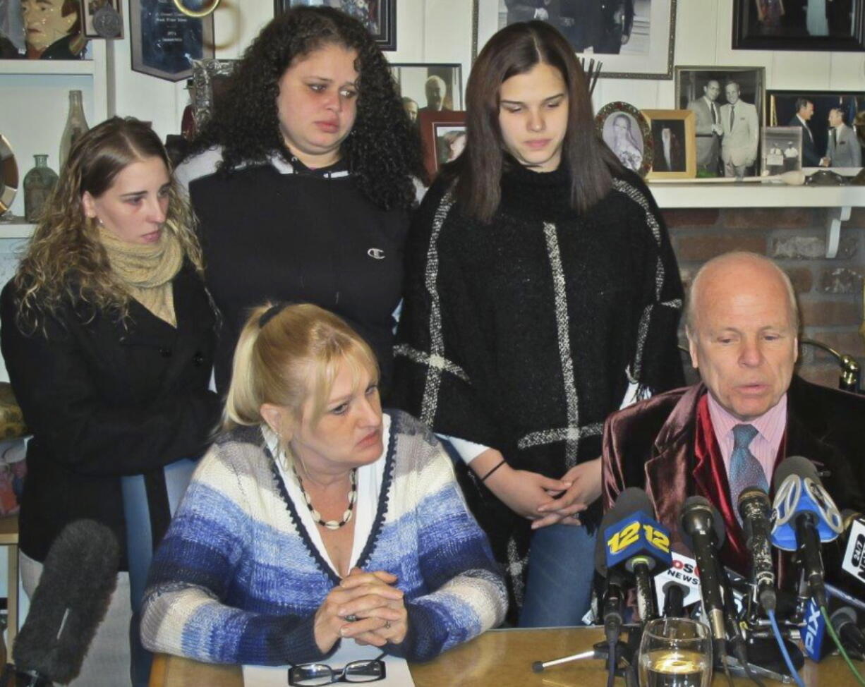 Sarra Elizabeth Gilbert, center, stands between her sisters Stevie Smith, left, and Sherre Gilbert, right, as her mother Mari Gilbert, seated left, and attorney John Ray, seated right, hold a press conference in February.