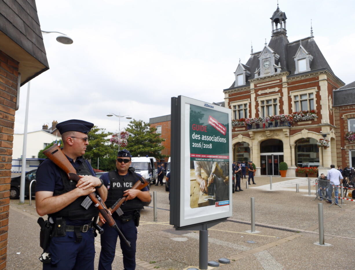 French police officers stand guard in front of the Saint-Etienne-du-Rouvray&#039;s city hall, Normandy, France, after an attack on a church that left a priest dead Tuesday. Two attackers invaded a church Tuesday during morning Mass near the Normandy city of Rouen, killing an 84-year-old priest by slitting his throat and taking hostages before being shot and killed by police, French officials said.