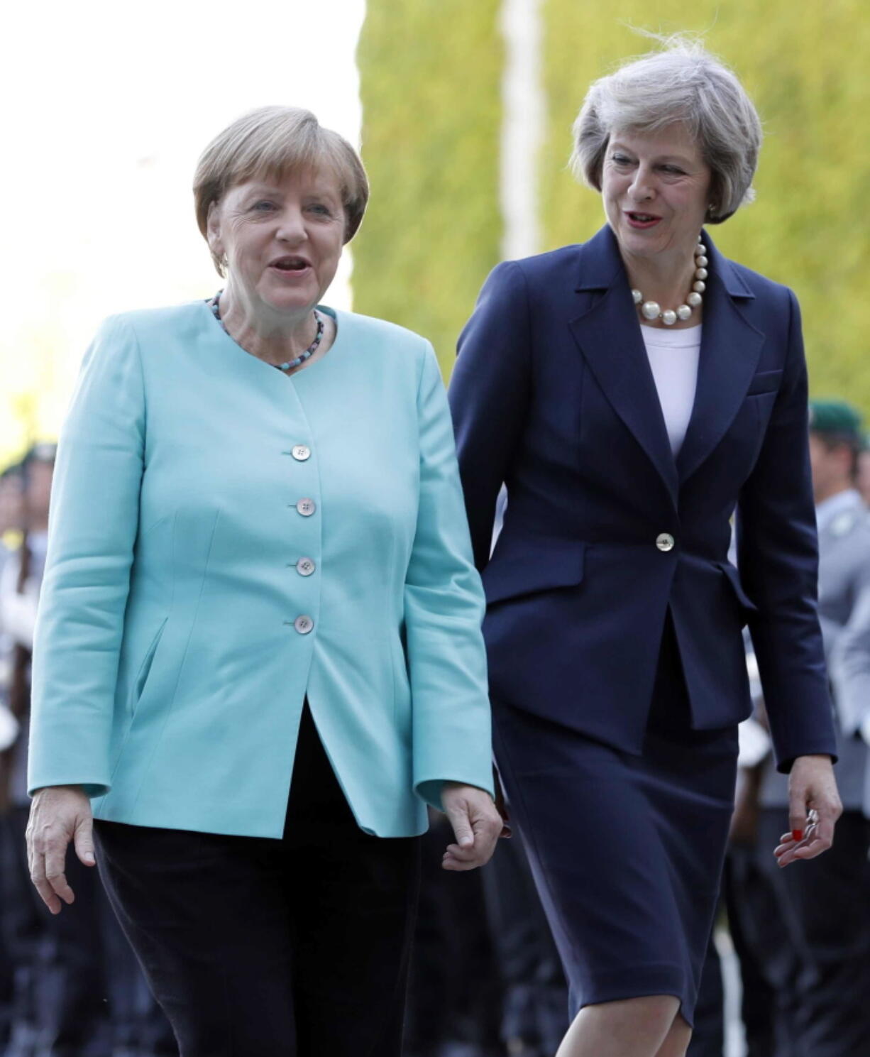 German Chancellor Angela Merkel, left, and British Prime Minister Theresa May chat during a military welcoming ceremony Wednesday in Berlin.