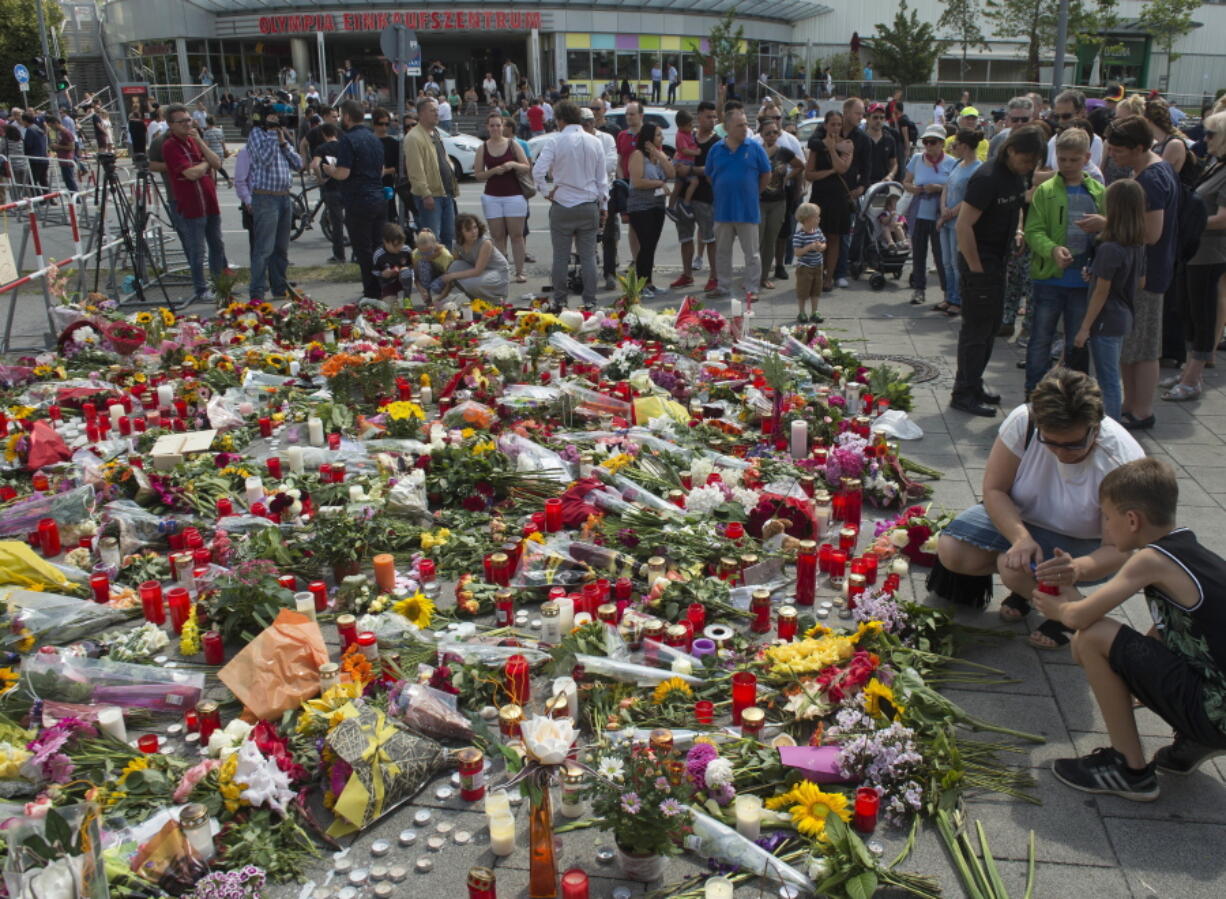 People mourn in front of the Olympia shopping center Sunday where a shooting took place leaving nine people dead two days ago in Munich, Germany.