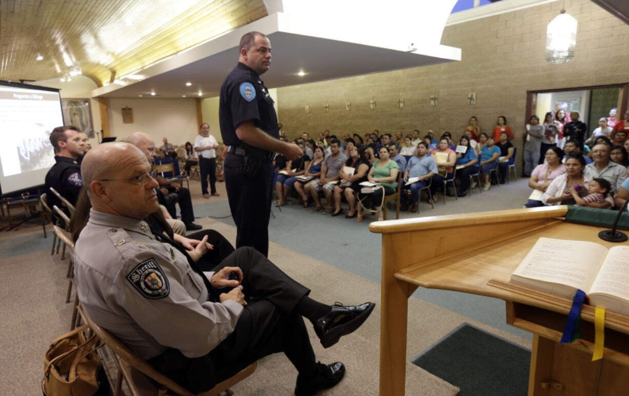 In this photo taken Wednesday, July 13, 2016 local law enforcement officers speak with members of the Hispanic community during a Faith Action ID drive at Holy Family Catholic Church in Hillsborough, N.C. More than 200 people with no legal U.S. identification gathered to learn how to use their new $10 ID cards to communicate with police.