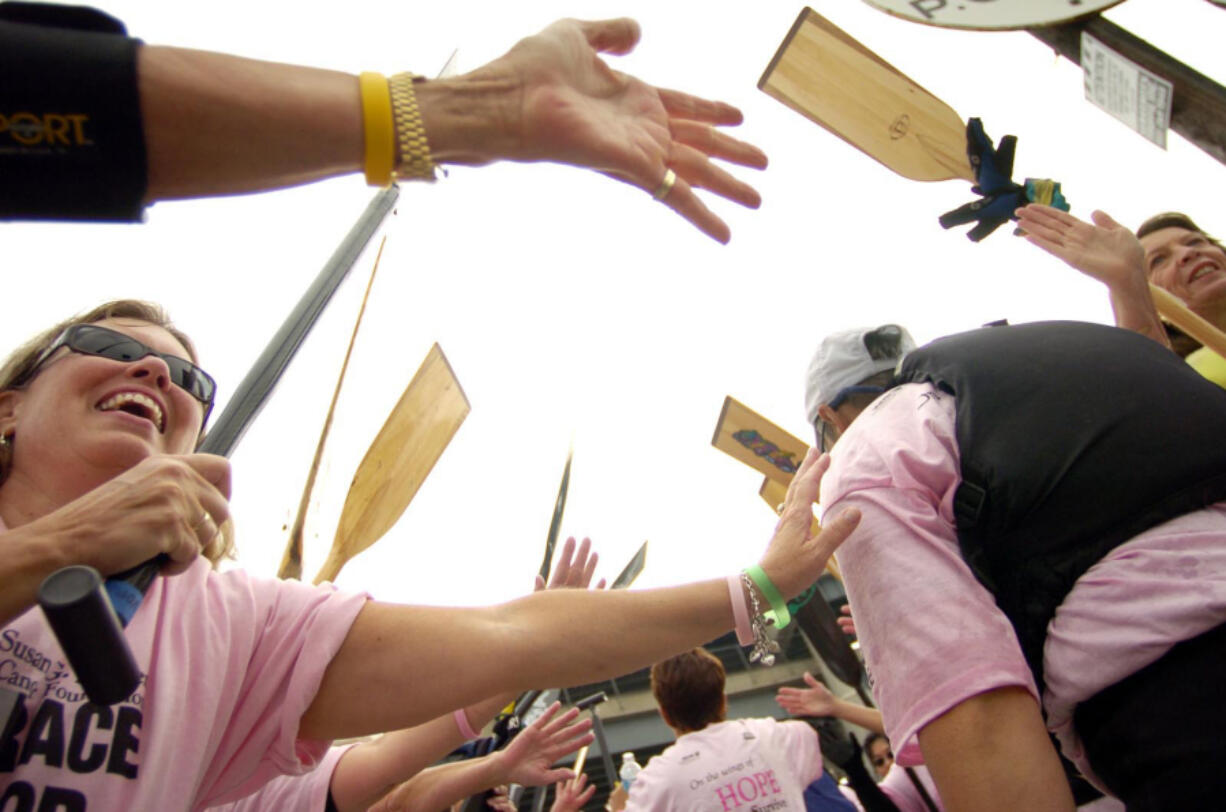 One team of breast cancer survivors form an arch with their oars, in honor of another team&#039;s members,  following a Row for the Cure dragon boat race.