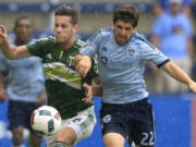 Portland Timbers forward Lucas Melano (26) and Sporting Kansas City midfielder Connor Hallisey (22) race for the ball during the first half of an MLS soccer match in Kansas City, Kan., Sunday, July 31, 2016.