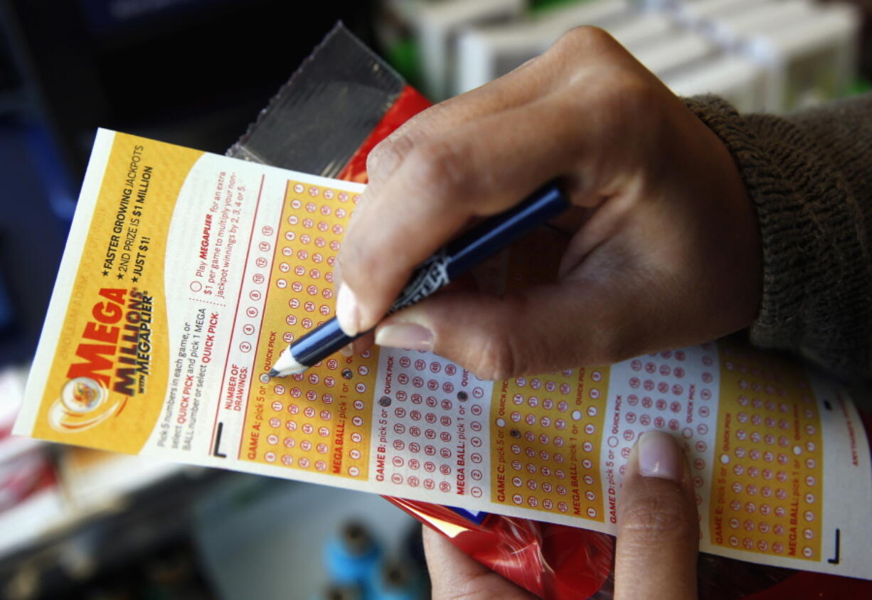 Sara Thompson picks numbers for the Mega Millions lottery at a convenience store in Chicago. T (AP Photo/Nam Y.