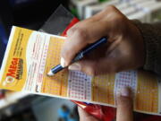 Sara Thompson picks numbers for the Mega Millions lottery at a convenience store in Chicago. T (AP Photo/Nam Y.