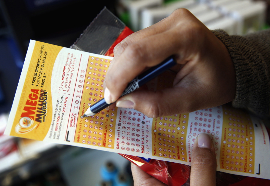 Sara Thompson picks numbers for the Mega Millions lottery at a convenience store in Chicago. T (AP Photo/Nam Y.