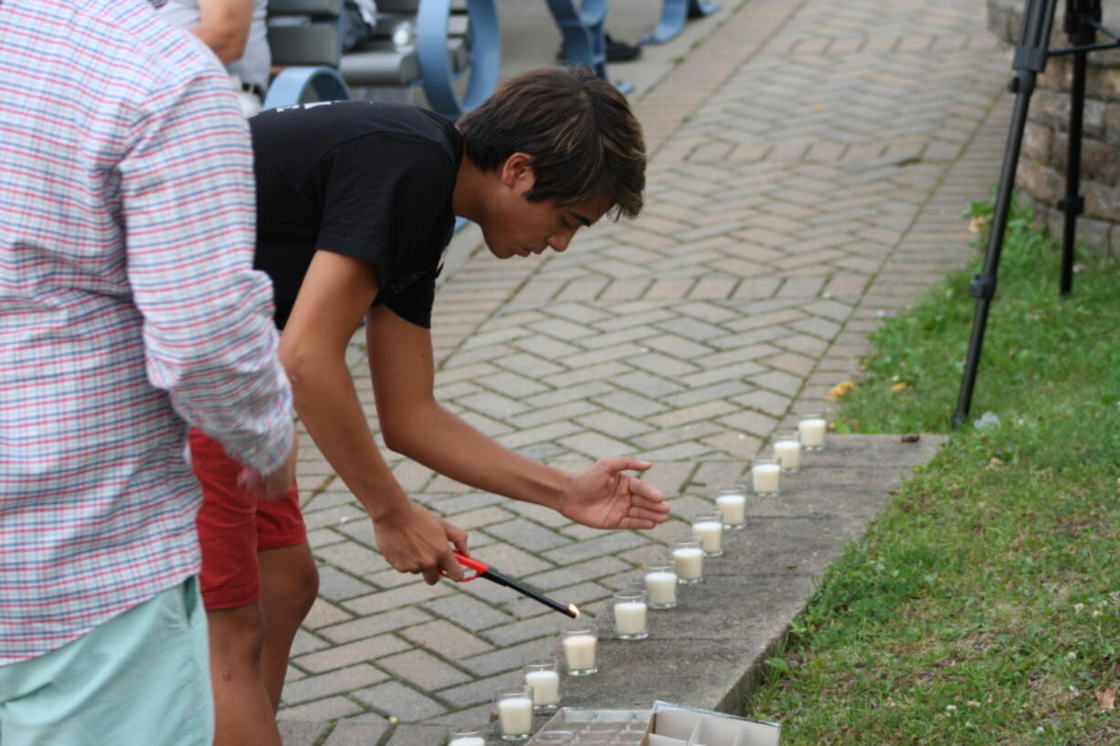 Antonio Ellis of St. Joseph helps light candles Tuesday, July 12, 2016, at a candlelight vigil at the John E.N. Howard Bandshell in St. Joseph, Mich. Hundreds of people across Berrien County were at the vigil to pay their respects to the two court officers that were shot and killed Monday.