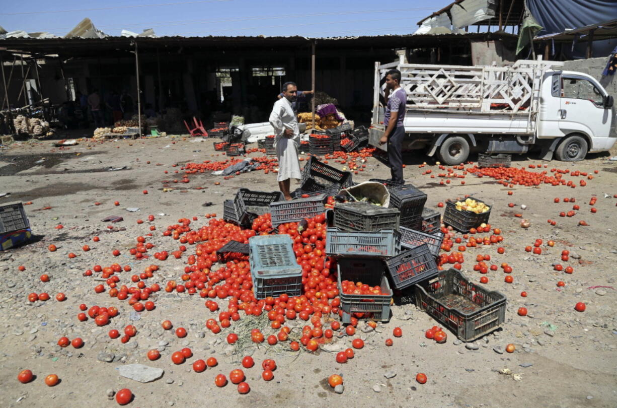 Civilians gather at the scene of a deadly suicide car bombing at an outdoor market in a Shiite-dominated district in northeastern Baghdad, Iraq, on Tuesday. The bomb on Tuesday, killed at least 10 people and injured tens of others, officials said. The developments came on the heels of two large-scale attacks claimed by the Islamic State group that killed more than 300 people last week.