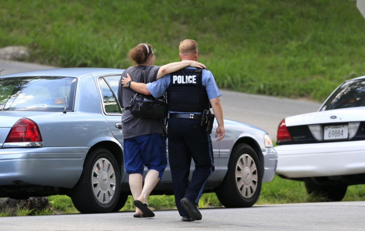 Kansas City, Kan., police officer Brad Lightfoot, right, walks Susan Goble to the shooting scene of a police officer in Kansas City, Kan., Tuesday. Goble knows the family of the fallen officer and hoped to place a wreath near the site of the shooting.