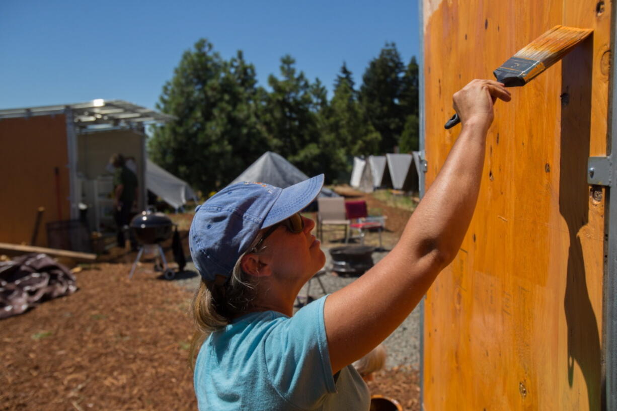 In this Wednesday, June 29, 2016 photo, Gina Wallace, a resident at the new camp for homeless women, paints a structure at the camp in northwest Eugene, Ore. The camp is the fourth Safe Spot Community opened and operated by Community Supported Shelters for homeless citizens in the Eugene and Springfield area.