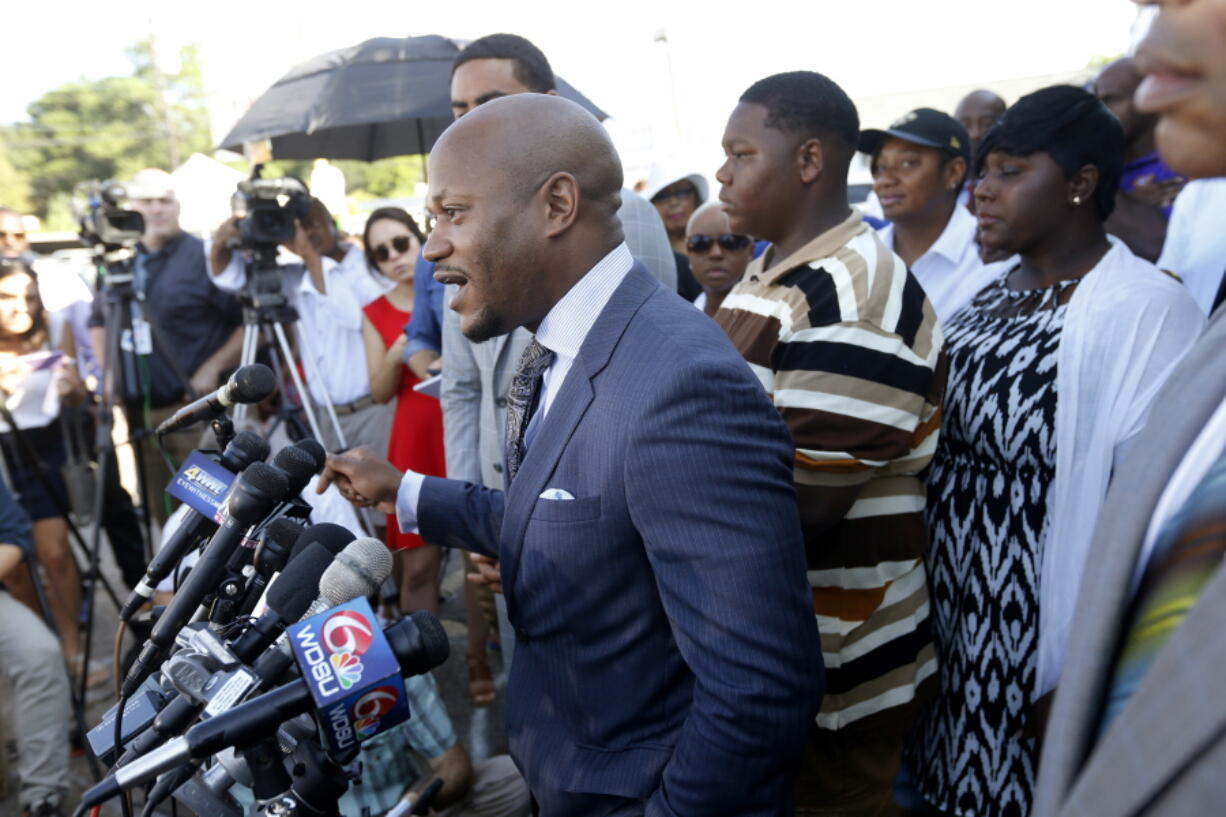 Attorney L. Chris Stewart speaks to the media with Cameron Sterling, second right, son of Alton Sterling, who was killed by Baton Rouge police last Tuesday, outside the Triple S Food Mart, where his father was killed, in Baton Rouge, La., on Wednesday. Sterling spoke out for the first time Wednesday, calling his father a good man and asking people not to resort to violence after his death.