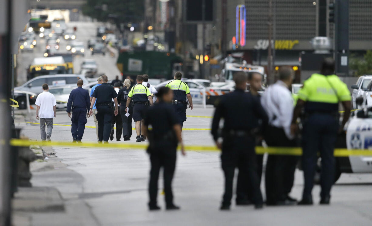 Investigators walk the scene of a shooting in downtown Dallas, Friday, July 8, 2016.   Snipers opened fire on police officers in the heart of Dallas during protests over two recent fatal police shootings of black men.