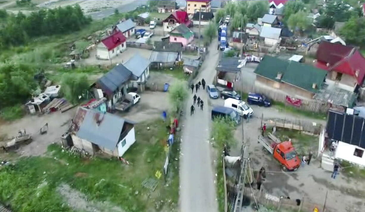 In an image taken from a Romanian Police handout video members of a special police unit walk on a road in the village of Berevoiesti, Romania. Dozens of vulnerable persons were kidnapped, chained up, whipped, fed scraps of food and forced into manual labor or fighting for entertainment over an eight-year period in rural southern Romania, prosecutors said Wednesday, with police rescuing three men and two boys aged 10-12 found chained up during searches at the homes of the suspects ??? members of an extended family.