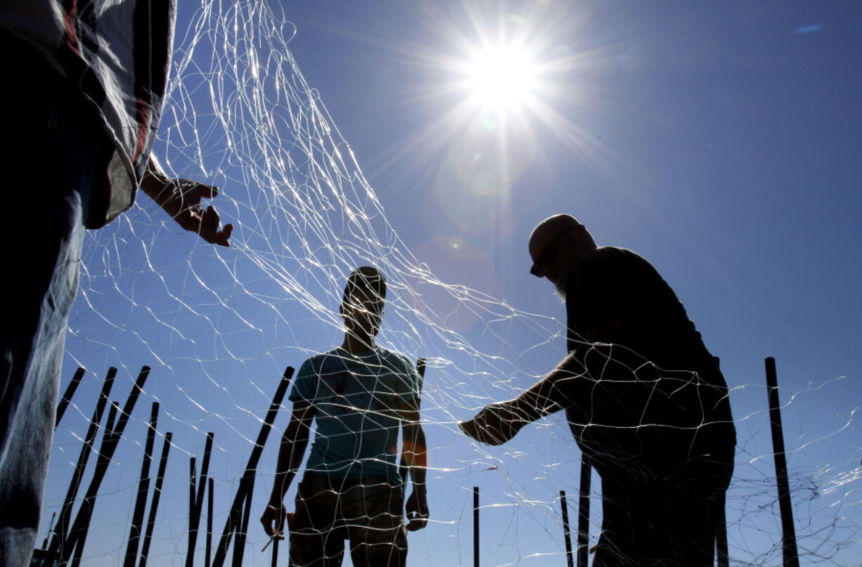 Commercial fishermen repair a gillnet near the mouth of the Columbia River in Astoria.