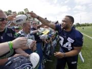 Seattle Seahawks' Thomas Rawls returns a dollar bill that he autographed after playfully threatening to keep it after the team's NFL football training camp Saturday, July 30, 2016, in Renton, Wash.