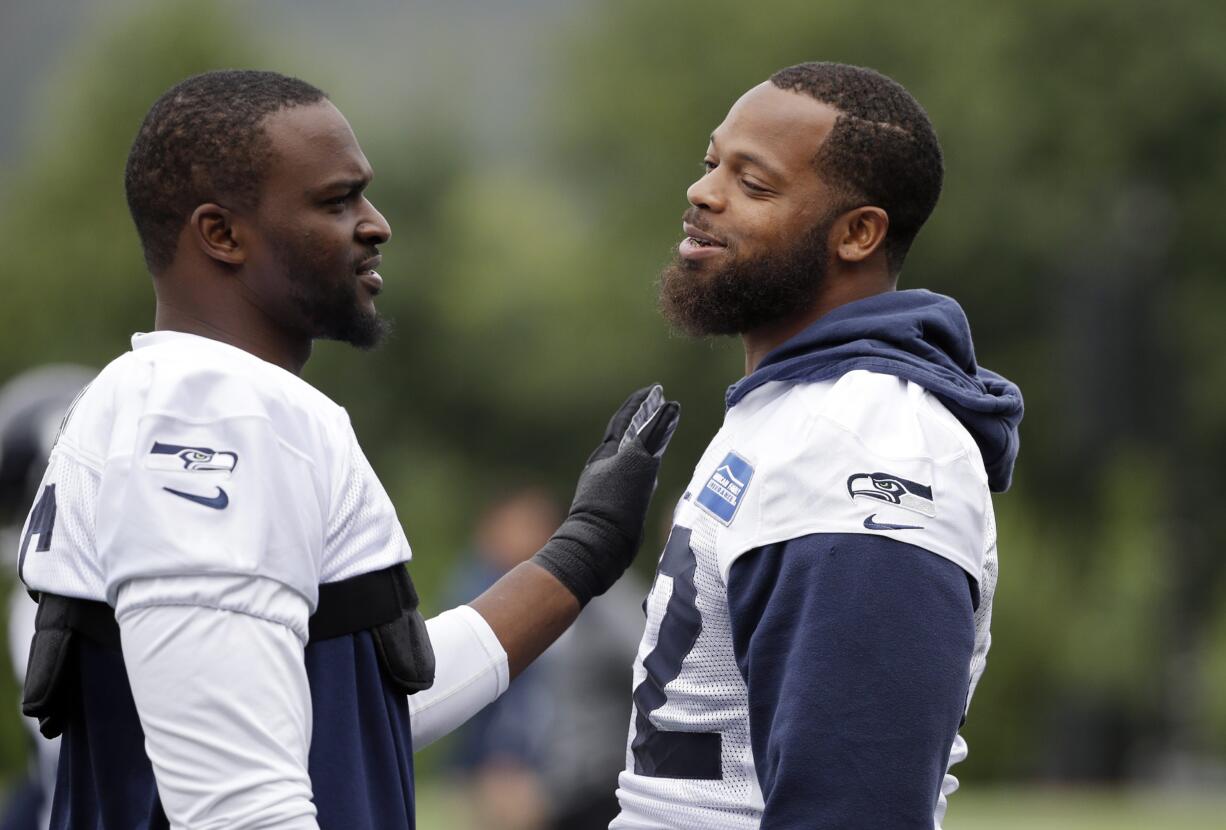 Seattle Seahawks' Michael Bennett, right, gets a pat from Cliff Avril during the team's NFL football training camp Saturday, July 30, 2016, in Renton, Wash.