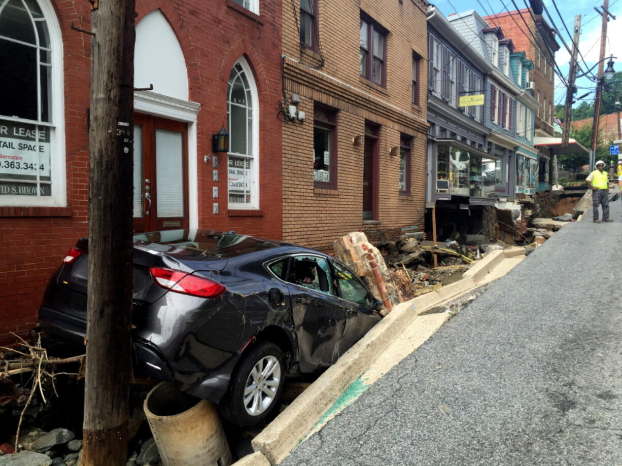 Workers gather by the sidewalk of Main Street that caved in after Saturday night&#039;s flooding in Ellicott City, Md., Sunday. Historic, low-lying Ellicott City, Maryland, was ravaged by floodwaters Saturday night, killing a few people and causing devastating damage to homes and businesses, officials said.