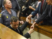 Oscar Pistorius, center, greets family members, right, as he is led down to the cells of the court in Pretoria, South Africa, in 2014. Pistorius is acquitted of murder after a dramatic seven-month trial that is broadcast live around the world. He is instead found guilty of manslaughter for killing Steenkamp and sentenced to five years in prison.