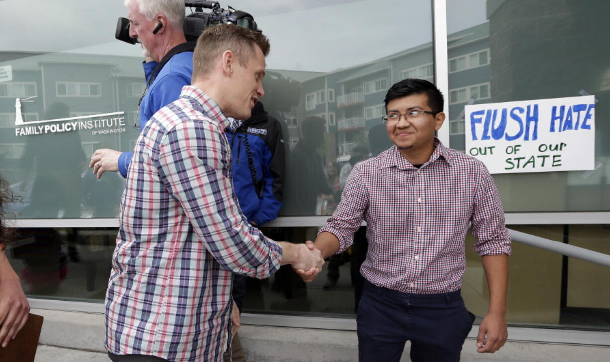 Joseph Backholm, left, executive director of the Family Policy Institute of Washington, shakes hands with Yes Segura, of the LGBTQ Allyship, after the two spoke following Segura&#039;s group&#039;s attempt to confront supporters of proposed Initiative 1515 on Thursday in Lynnwood.