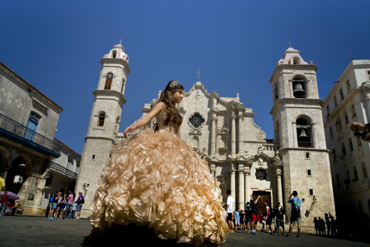 A &quot;quinceanera&quot; poses during her photo session in front of the cathedral as tourists line up to enter the building, in Havana, Cuba. Scheduled commercial airline service to Havana from 10 American cities won tentative government approval Thursday, advancing President Barack Obama&#039;s effort to normalize relations with Cuba.