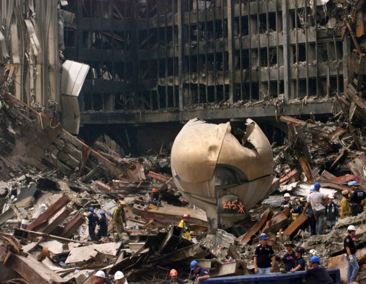 Pedestrians pass Fritz Koenig&#039;s &quot;The Sphere&quot; Thursday in Battery Park in New York.  At top, the outdoor sculpture, which once stood in between the two towers, lies in the wreckage of the World Trade Center on Sept. 24, 2001.