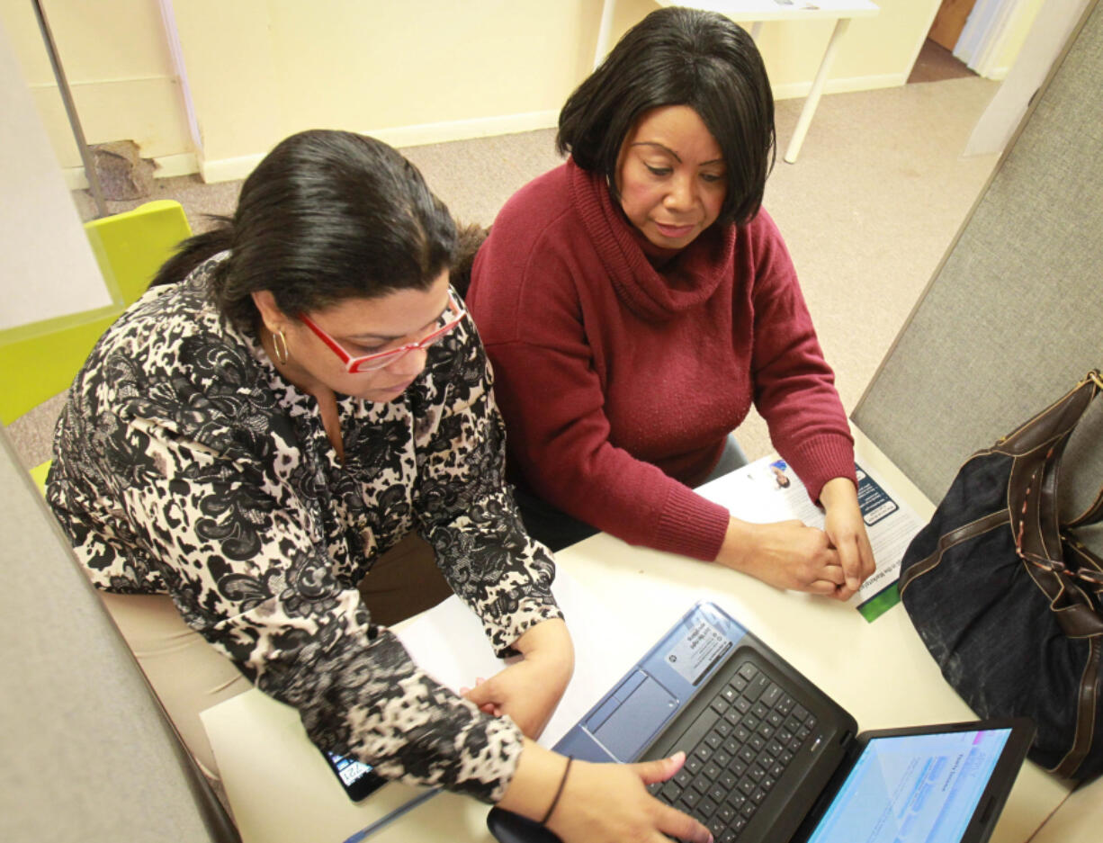 Certified navigator Azia Troutman, left, helps Jacqueline Foster, of Dayton, with a Medicaid application at the Helping Hands Community Center in this 2014 file photo from Dayton, Ohio.