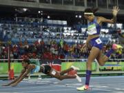 Bahamas' Shaunae Miller falls over the finish line to win gold ahead of United States' Allyson Felix, right, in the women's 400-meter final during the athletics competitions of the 2016 Summer Olympics at the Olympic stadium in Rio de Janeiro, Brazil, Monday, Aug. 15, 2016.